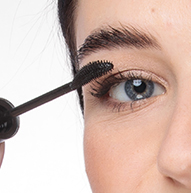 Uma mulher aplica rímel com pincel, dando volume aos cílios e aperfeiçoando a maquiagem dos olhos.